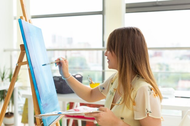 芸術学校、芸術大学、若い学生のグループのための教育。幸せな若い女性の笑顔、女の子が絵を描くことを学んでいます。