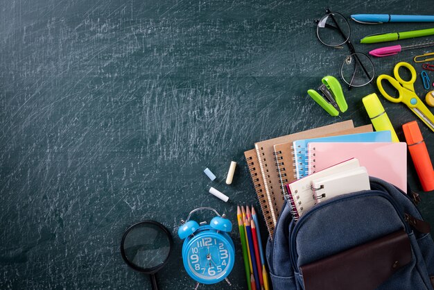 School backpack and school supplies with chalkboard background