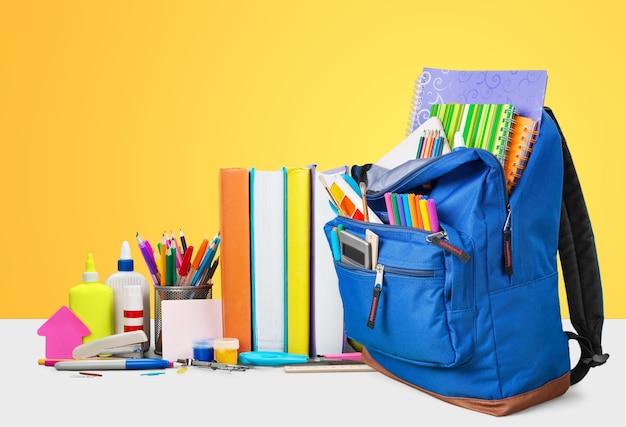 school backpack with school stationery on a colored background. Concept back to school.