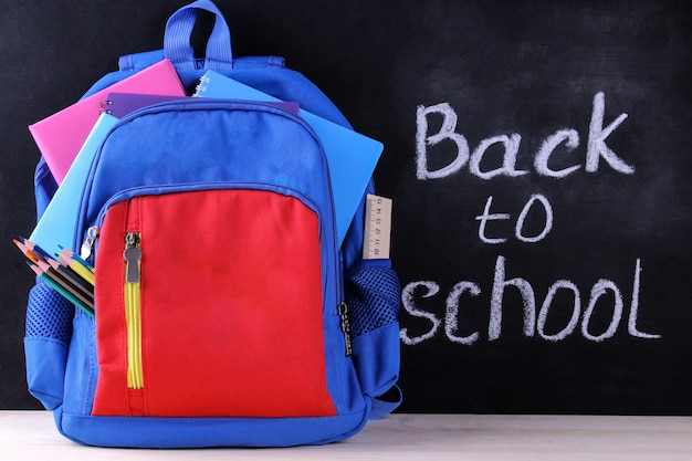 School backpack with  school supplies on the background of a school board