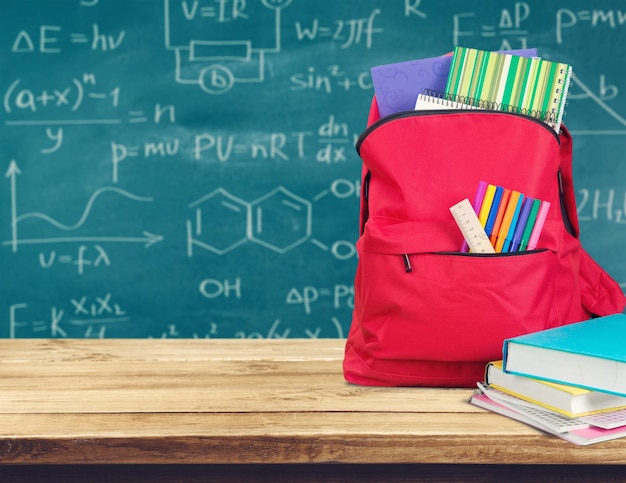 School backpack with stationery on wooden background