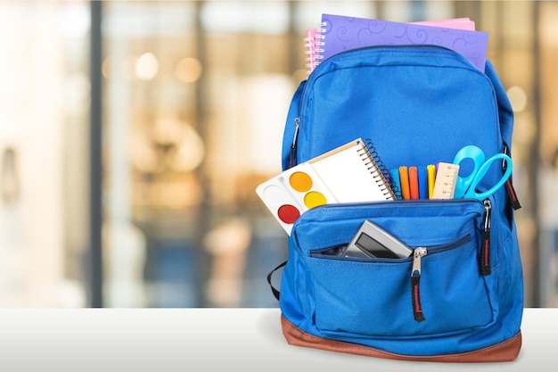 School Backpack with stationery on wooden table