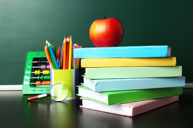 School books on desk near chalkboard