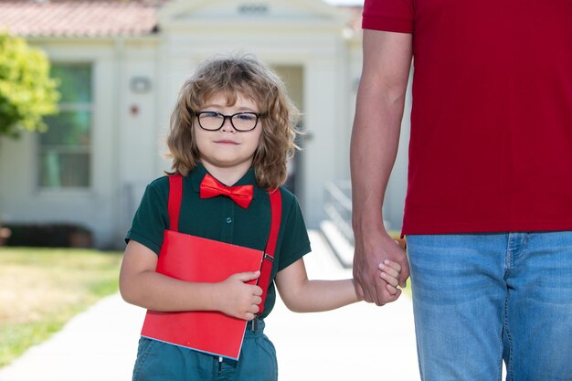 School boy going to school with father teachers day portrait of happy nerd pupil holding teachers hand