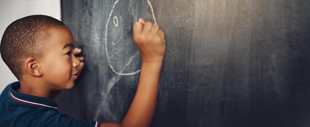 School chalk and boy drawing on a board for child development creativity and art for learning academic creative and young kid student writing on a blackboard in the classroom with mockup space