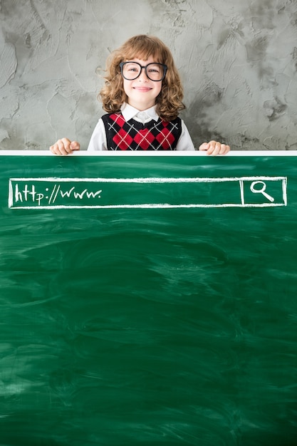 School child in class Happy kid against green blackboard Education concept