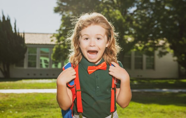 Photo school child concept amazed pupil kid in school uniform with backpack outdoor portrait of excited nerd schoolboy