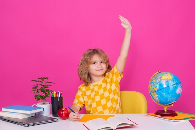 School child raising hands willing to answer question Smart caucasian school boy kid pupil student going back to school School child isolated on red pink studio background