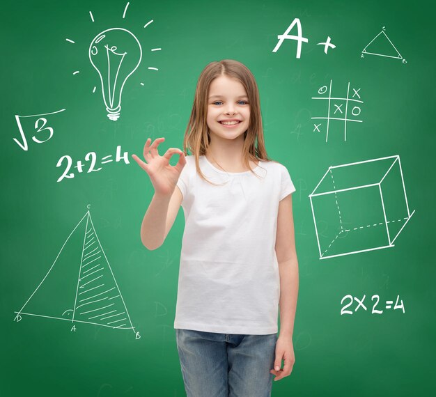 school, childhood, gesture and education concept - smiling little girl in white blank t-shirt showing ok sign