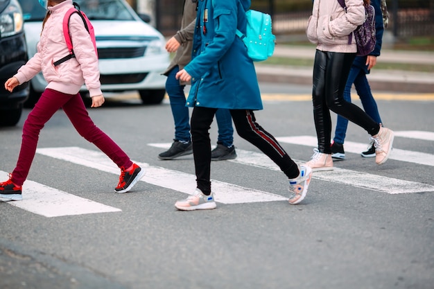 Photo school children cross the road in medical masks. children go to school.