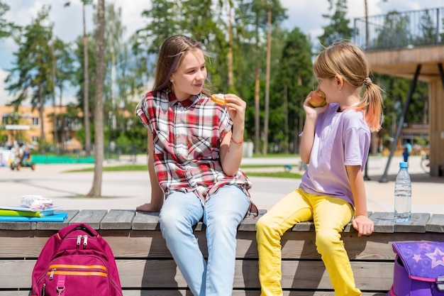 建物の外で一緒に昼食をとっている小学生。昼食を共有する庭の女の子