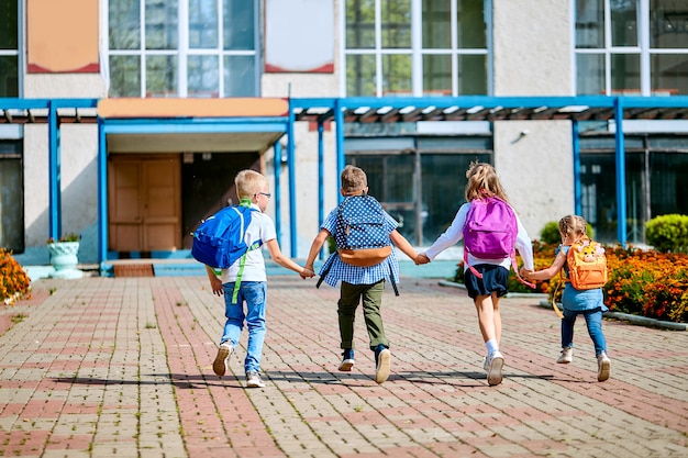 School children with backpacks running out of school