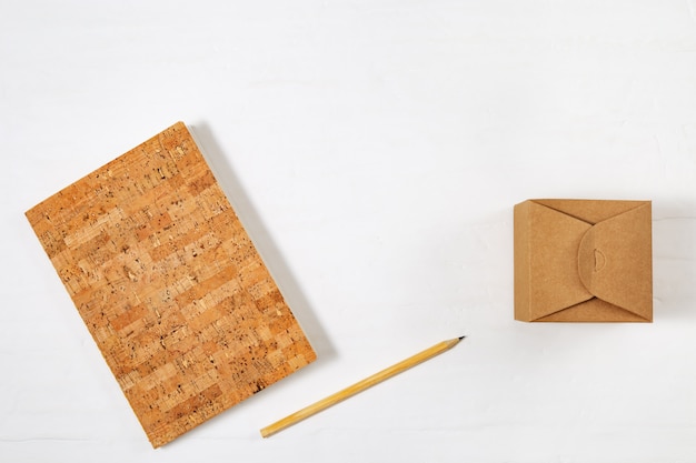School closed notebook, wooden pencil and craft box on tabletop. Top view with copy space, flat lay photography.