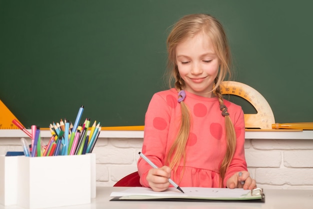 School concept kind schrijven op leerboek kleine student huiswerk op basisschool kleine gir