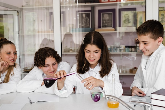 학교 교육 화학 수업의 쾌활한 반 친구들은 실험을 위해 액체가 든 플라스크를 들고 실험실에서 수업 시간에 함께 공부합니다.