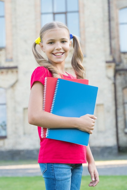 School education concept. Achieving high standards. Cute little bookworm. Little girl school student. Secondary school student. Cute smiling small child hold books educational institution background.