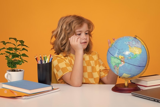 School and education concept portrait of cute child school boy looking at globe during geography