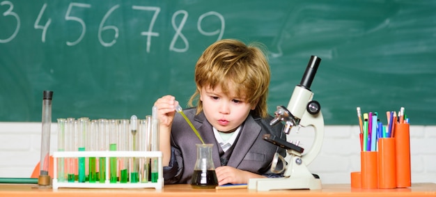 School education. Explore biological molecules. Toddler genius baby. Technology and science concept. Boy near microscope and test tubes in school classroom. Kid study biology and chemistry in school.