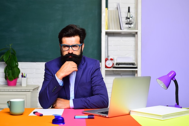 School education knowledge concept male teacher sits on desk university student in glasses over