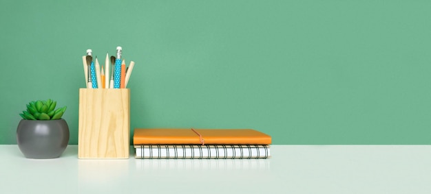 School equipment on white table green wall background Education Wooden supplies Back to school Desk