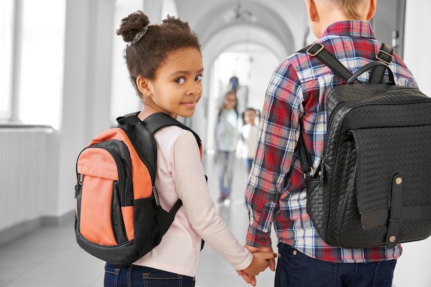 Photo school girl brunette african holding stylish boy by hand