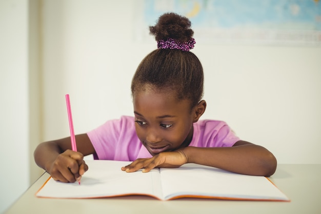 School girl doing homework in classroom