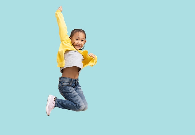 Photo school girl happy smiling asian student school kid jumping for joy full body portrait isolated on pastel plain light blue background