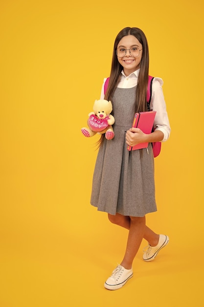 School girl hold toy school children with favorite toys on yellow isolated background childhood