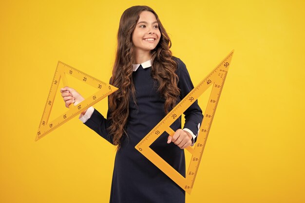 School girl holding measure for geometry lesson isolated on yellow background measuring equipment student study math