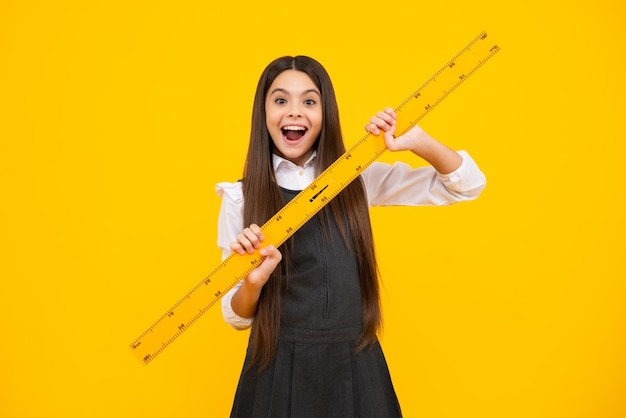 School girl holding measure for geometry lesson isolated on yellow background measuring equipment