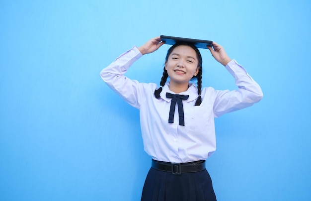 School girl holding tablet on blue background