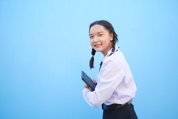 School girl holding tablet on blue background