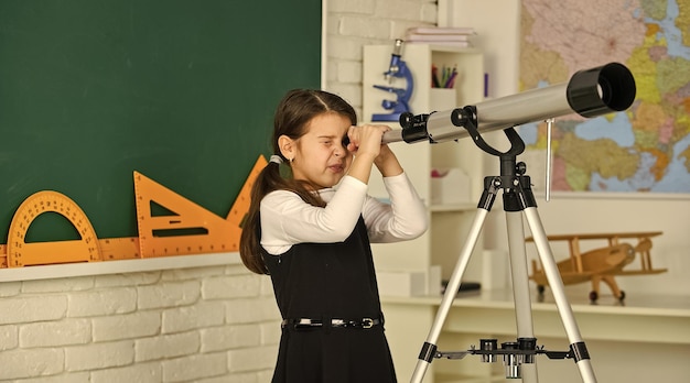 School girl looking through telescope little girl using\
telescope telescope on tripod school subjects set school astronomy\
lesson exploring space and planets of new galaxies