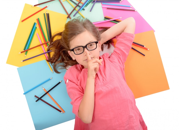 School girl lying on the floor with color pencils