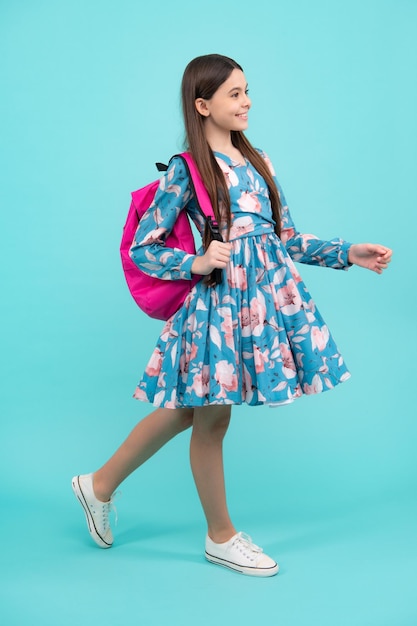 School girl in school uniform with school bag Schoolchild teenager hold backpack on blue isolated background Happy teenager positive and smiling emotions