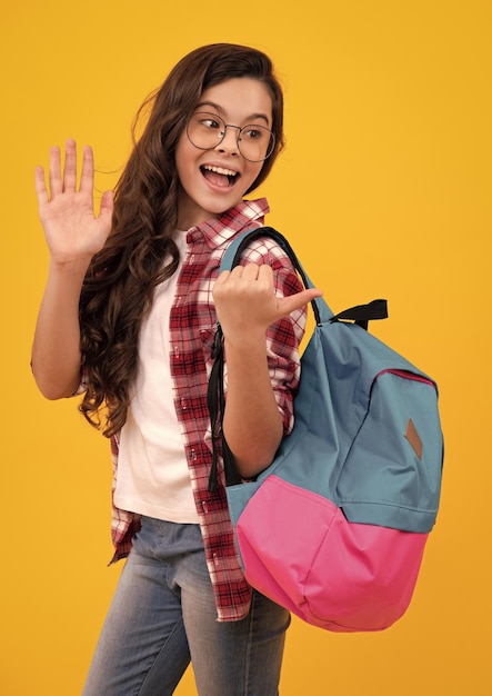 학교 가방을 든 교복을 입은 여학생 여학생 십대는 노란색 외진 배경에 배낭을 들고 있습니다. 행복한 십대 긍정적이고 십대 소녀의 웃는 감정