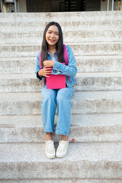 School girl Smiling and sitting on stair hold book at school