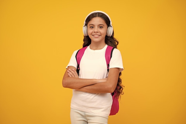 노란색 격리된 스튜디오 배경 학교 및 음악 교육 개념에 헤드폰을 끼고 학교로 돌아가는 여학생