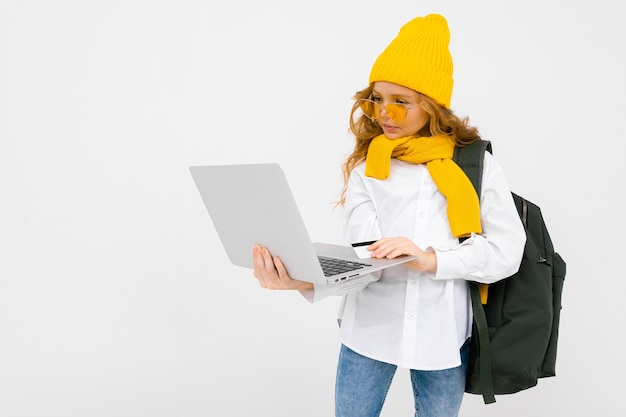 School girl with a backpack behind and a laptop with courses for learning steps on a white background.