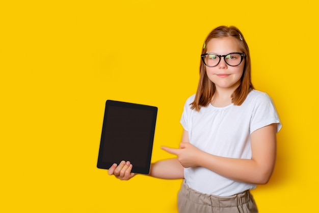 a school girl with glasses points at a tablet