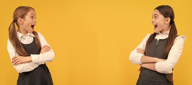 School girls friends surprised little kids look at each other with open mouths in formal school uniforms portrait of schoolgirl student studio banner header school child face copyspace