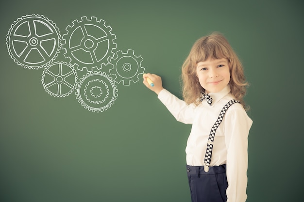 School kid in class. Happy child against green blackboard. Education concept