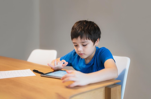집에서 온라인 수업을 배우는 학교 아이 집안 과제를 위해 태블릿을 사용하는 아이 온라인 비디오 통화로 공부하는 소년 Elearning 또는 Homeschooling 교육 개념