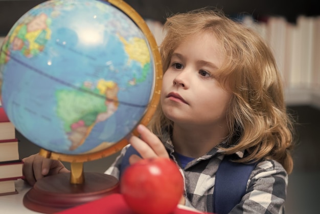 Foto bambino scolastico che guarda il globo nella biblioteca della scuola elementare bambino della scuola primaria alunno che va a studiare studente scolastico intelligente che impara i bambini studiano il concetto di conoscenza ed educazione