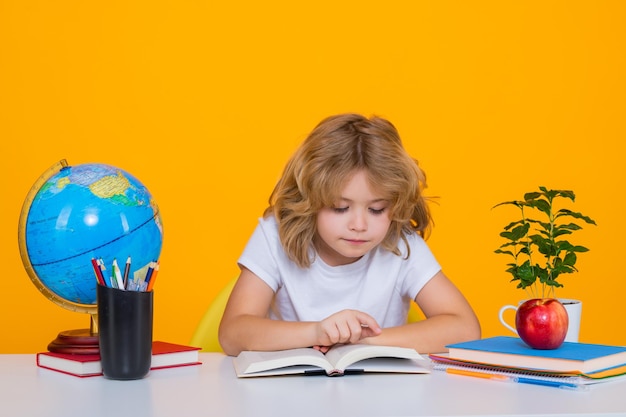 School kid reading book Nerd pupil boy from elementary school with book isolated on yellow studio background Smart genius intelligence kid ready to learn Back to school