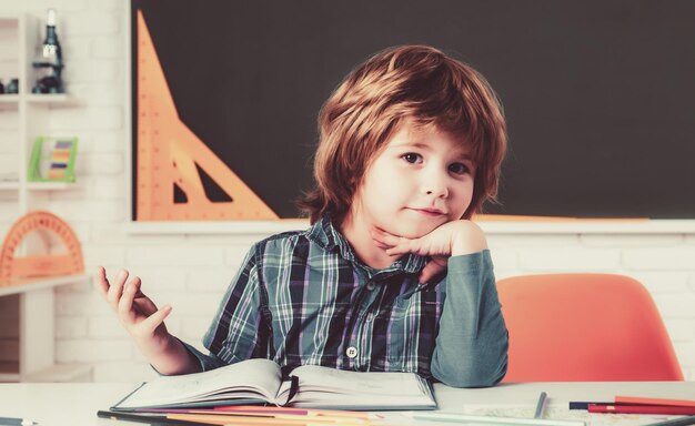 I bambini della scuola contro il bambino della lavagna verde si preparano per la scuola materna carina in classe