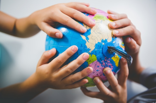 school kids holding globe in classroom