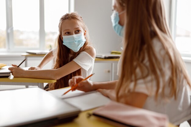 Foto ragazzi delle scuole che tengono in mano matite e usano i quaderni in classe