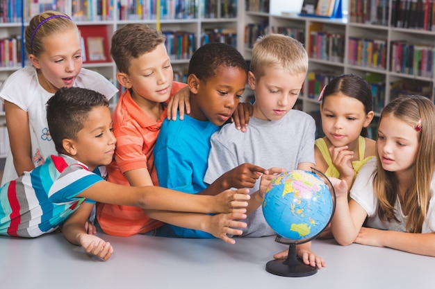 School kids looking at globe in library