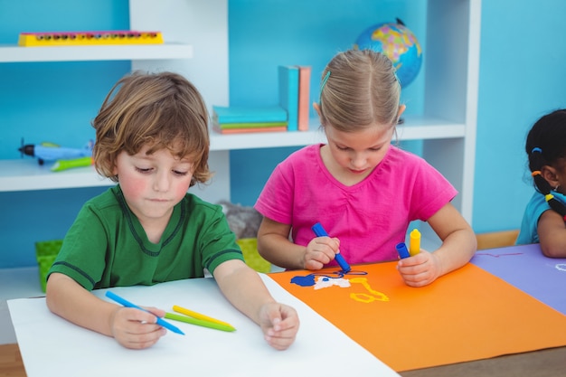 机の上に芸術を作るスクールの子供たち